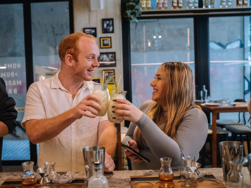 A couple smiling at one another while clinking cocktail classes together